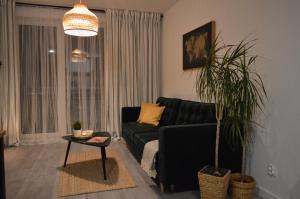 a living room with a black couch and a table at Apartament M&I in Koszalin
