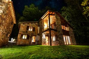 una vieja casa de piedra por la noche con luces en Masias de Rocabruna en Rocabruna