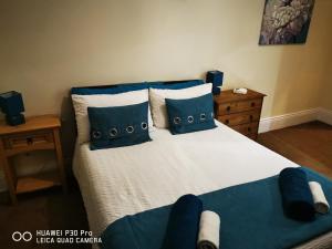 oddfellowsbandb في Blythe: غرفة نوم مع سرير ووسائد زرقاء وبيضاء