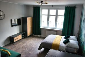 a bedroom with a bed and a window with green curtains at Pośród Drzew Studio Świętojańska Gdynia in Gdynia