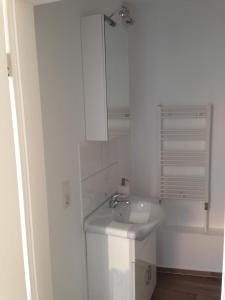 ein weißes Badezimmer mit einem Waschbecken und einem Spiegel in der Unterkunft Ferienhaus Brücke in Quedlinburg