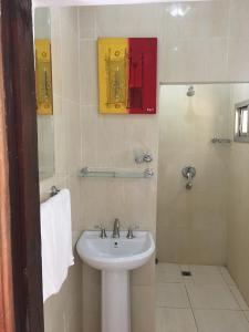 Baño blanco con lavabo y espejo en Pelican Residence, en Fajara