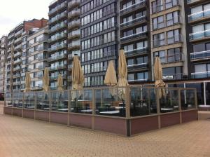 a restaurant with closed umbrellas in front of a building at Hotel De Zeebries Budget in Middelkerke