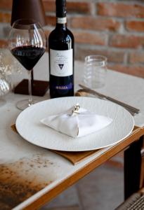 einen Teller mit einer Serviette auf dem Tisch und einer Flasche Wein in der Unterkunft Residenza San Vito in Calamandrana