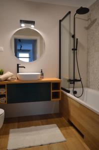 a bathroom with a sink and a tub and a mirror at Apartament M&I in Koszalin
