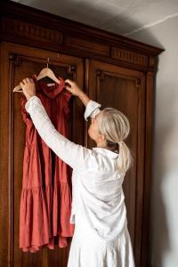a woman is holding a red shirt on a closet at Residenza San Vito in Calamandrana