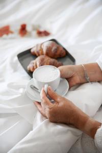 eine Person, die eine Tasse und einen Teller Essen hält in der Unterkunft Residenza San Vito in Calamandrana