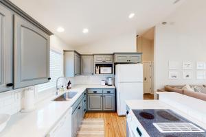 a kitchen with white cabinets and a white refrigerator at The Surfbird in Pacific City