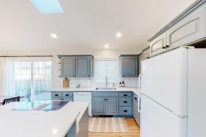 a kitchen with blue cabinets and a white refrigerator at The Surfbird in Pacific City
