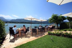 a group of people sitting at tables on a deck near the water at Hotel Seehang Garni in St. Wolfgang