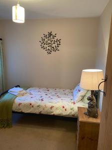 a bedroom with a bed and a lamp on a table at Spaniel Cottage with views of Ham hill, Stoke sub Hamdon in Martock
