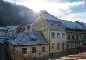 a building with a roof with the sun in the background at Apartament Agnes in Braşov