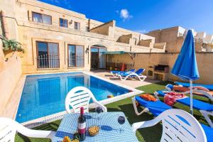 a swimming pool with chairs and a table and umbrella at Ta Danjela Villa Sleeps 8 with Pool in Xagħra