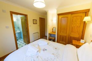 a bedroom with a white bed and a bathroom at The Raven in Crianlarich