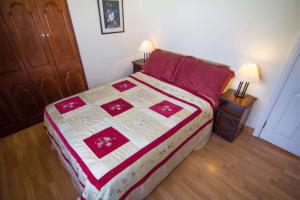 a bedroom with a bed with a red and white quilt at Stunning 3-Bedroom House with Private Garden in Carracastle