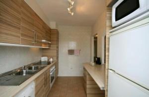 uma cozinha com armários de madeira, um lavatório e um frigorífico em Beautiful Townhouse Internet Air Con 5 Guests em Estepona