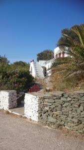 uma parede de pedra ao lado de uma casa com uma palmeira em Stunning House in Sifnos Island Chrisopigi em Chrisopigi
