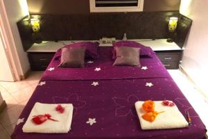 a bed with a purple blanket with stuffed animals on it at Villa Zenith in Case-Pilote