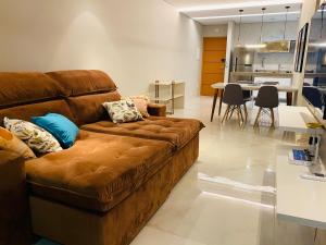 a living room with a brown couch and a table at Luxo em Ubatuba C/ Vista Montanha e Mar no Centro in Ubatuba