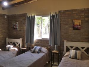 1 dormitorio con 2 camas y ventana en Cabañas EL AGUARIBAY en Barreal