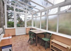 a conservatory with a table and chairs and windows at Lovely Large home 10 Minute Walk to Barmouth Beach in Barmouth