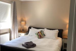 1 dormitorio con 1 cama con sábanas y almohadas blancas en Discreet luxury Super house!, en Gleann Maghair