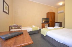 Habitación de hotel con 2 camas, mesa y TV. en Central Springs Inn, en Daylesford