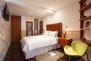 a bedroom with a white bed and a green chair at Casa del Balcon in Baños