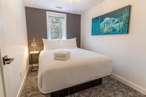 雷夫尔斯托克Basecamp Resorts Revelstoke的卧室里有一张铺着白色床单的床和一扇窗户