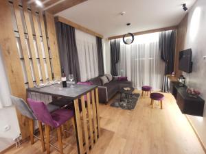 a kitchen and living room with a table and purple chairs at Apartmani Zimski Ples Jahorina in Jahorina