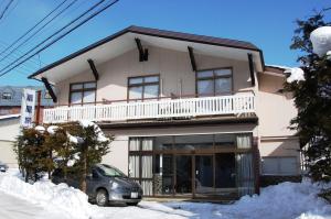 a house with a car parked in front of it at Ougiya Ryokan in Hakuba