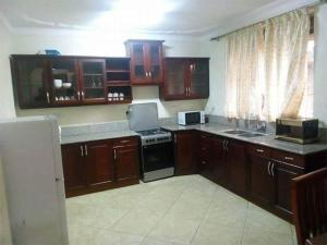 a kitchen with wooden cabinets and a stove top oven at Go around Kampala all day to return to your wonderful apartment in Kampala