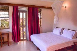 a bedroom with a large bed with red curtains at Go around Kampala all day to return to your wonderful apartment in Kampala