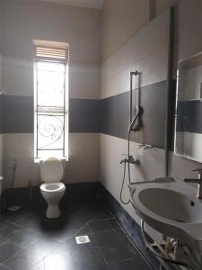 a bathroom with a toilet and a sink and a window at Go around Kampala all day to return to your wonderful apartment in Kampala