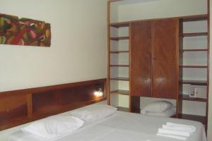 a bedroom with a bed with a wooden headboard and shelves at BOULEVARD DA PRAIA Apart Hotel Beira mar in Porto Seguro +7 photos