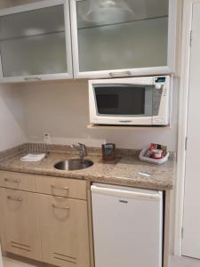 una piccola cucina con forno a microonde e lavandino di ApartHotel no Jurerê Beach Village a Florianópolis