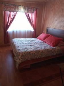 Un dormitorio con una cama con almohadas rojas y una ventana en Flor/Victoria, en Villarrica