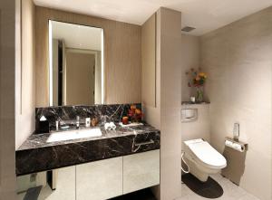 uma casa de banho com um lavatório, um WC e um espelho. em Pan Pacific Serviced Suites Orchard, Singapore em Singapura