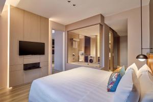 um quarto com uma grande cama branca e uma televisão de ecrã plano em Pan Pacific Serviced Suites Orchard, Singapore em Singapura