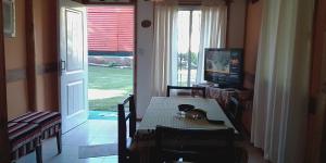 a dining room with a table and a television and a window at Cabañas los Plátanos in La Granja