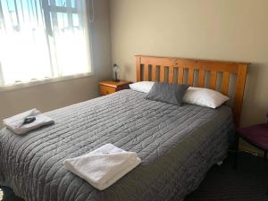 een slaapkamer met een bed met twee handdoeken erop bij Catlins Inn in Owaka