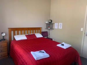 a bedroom with a red bed with towels on it at Catlins Inn in Owaka