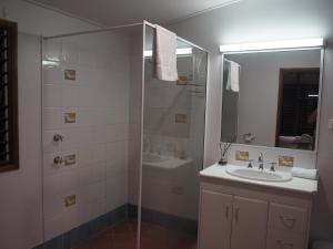 een badkamer met een douche, een wastafel en een spiegel bij Cassawong Cottages in Mission Beach