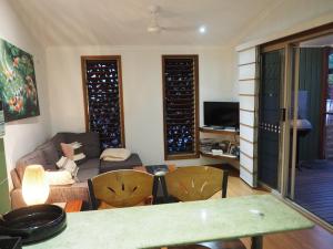 sala de estar con sofá, mesa y sillas en Cassawong Cottages en Mission Beach
