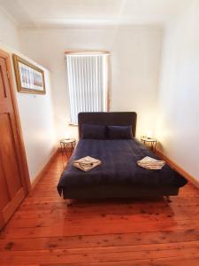 ein Schlafzimmer mit einem Bett mit einer blauen Decke und einem Fenster in der Unterkunft Bellview Holiday House in Wentworth