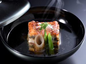 a black bowl with a piece of fish and vegetables at Muromachi Yutone Kyokoyado in Kyoto