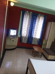 um quarto com uma televisão, um sofá e uma janela em HOTEL HIGHLAND RESIDENCY em Mangalore