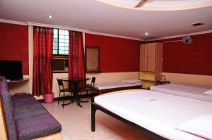 um quarto com 2 camas, uma mesa e uma televisão em HOTEL HIGHLAND RESIDENCY em Mangalore