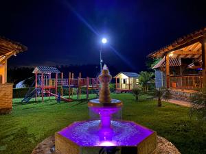 una fuente en un patio con un parque infantil por la noche en La Victoria Hotel Campestre, en Quimbaya