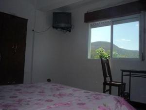 a bedroom with a bed and a tv and a window at Hotel Ruma in Salta